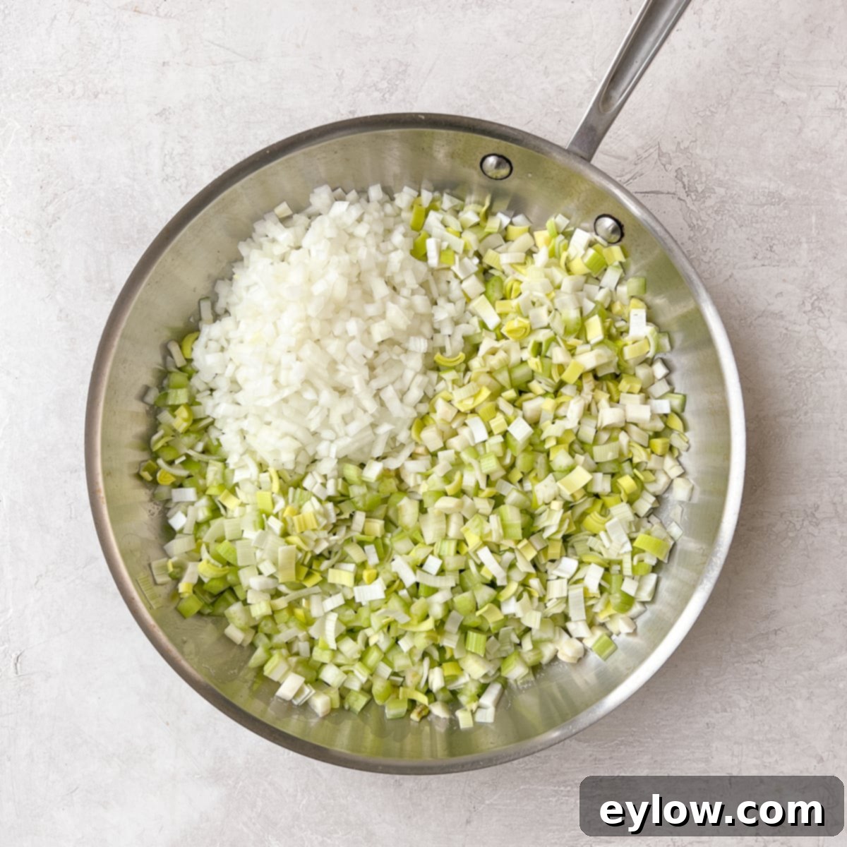 Finely chopped stuffing vegetables (onions, leeks, fennel, celery) in a stainless steel fry pan, ready to sauté.