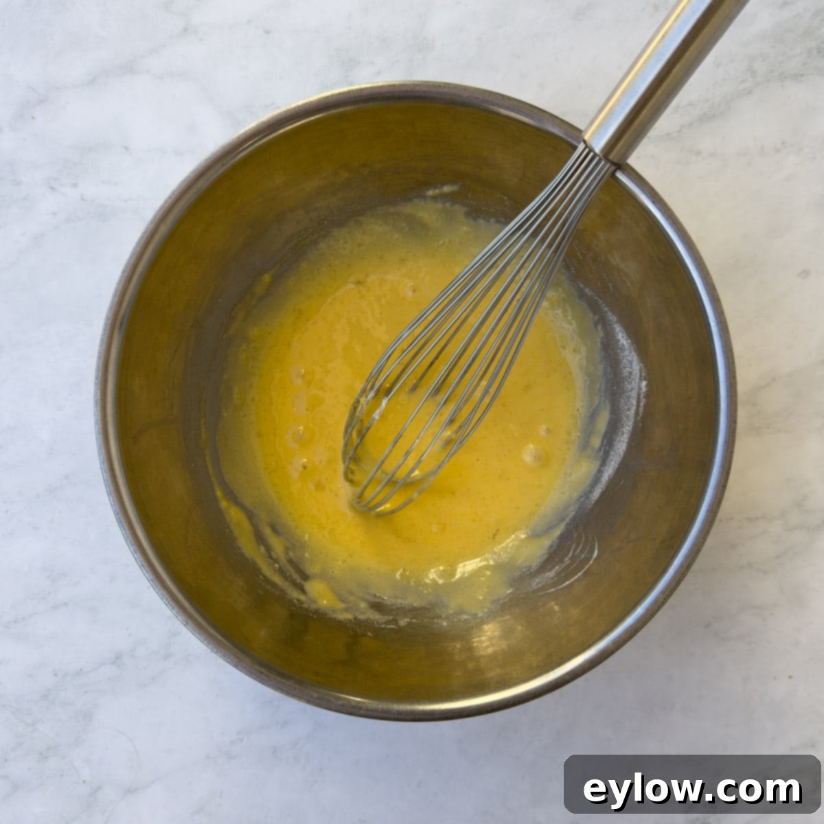 Velvet Pumpkin Mousse No-Bake Treat 6 Stainless steel bowl with yellow egg yolks and a whisk, showing the smooth mixture.