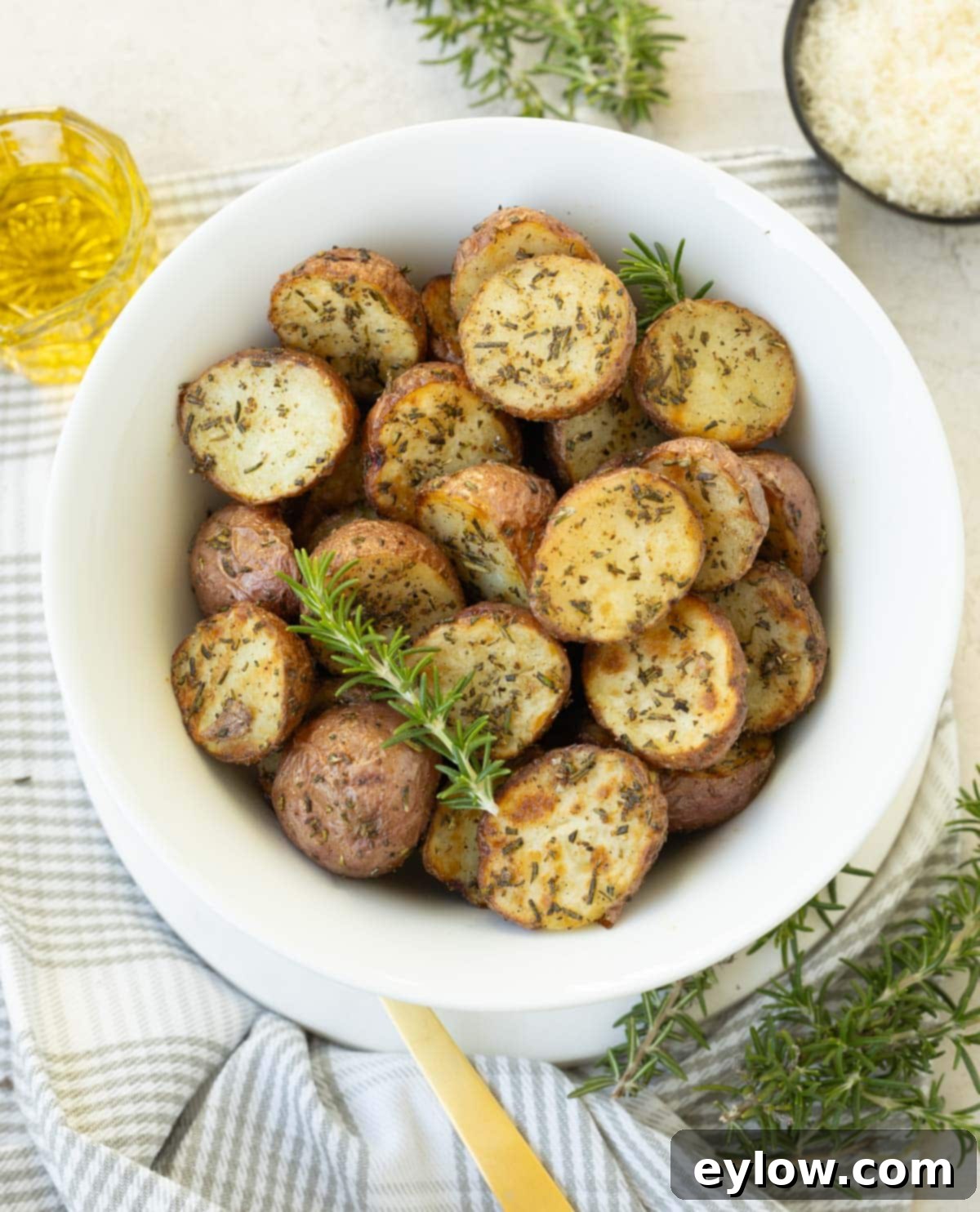 Golden Crispy Red Potatoes: Air Fried or Oven Roasted 2 A white bowl of golden, browned air fryer red potatoes with rosemary.