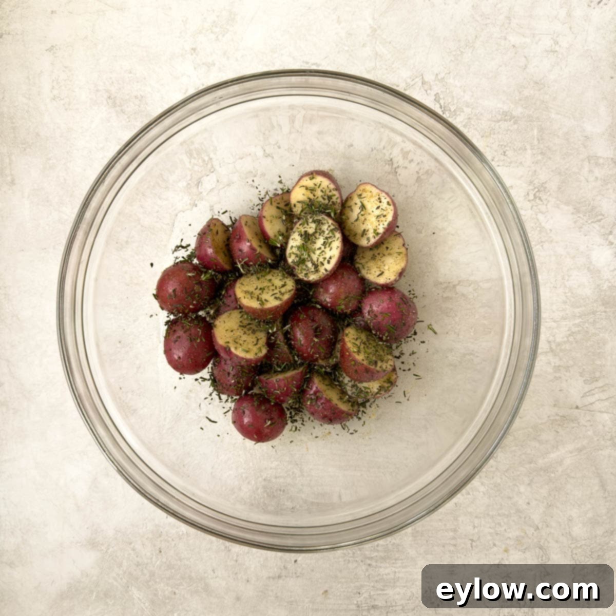 Golden Crispy Red Potatoes: Air Fried or Oven Roasted 4 Glass bowl with halved baby red potatoes with olive oil and herbs.