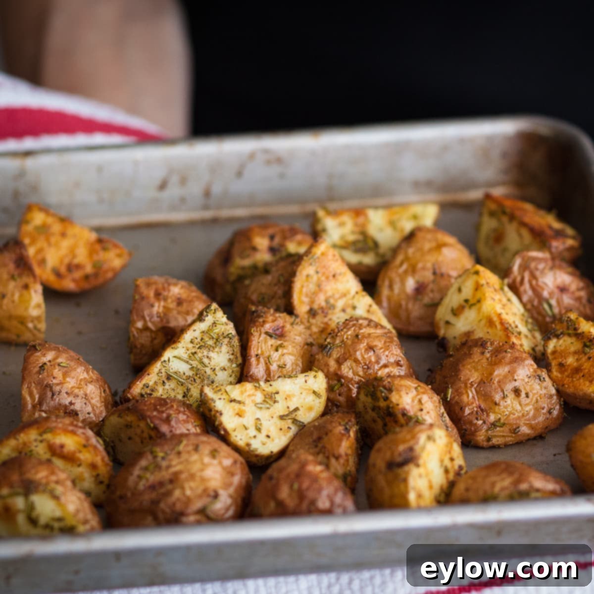 Roasted Red Potatoes Crisp brown roasted red potatoes on a baking tray with bits of rosemary.