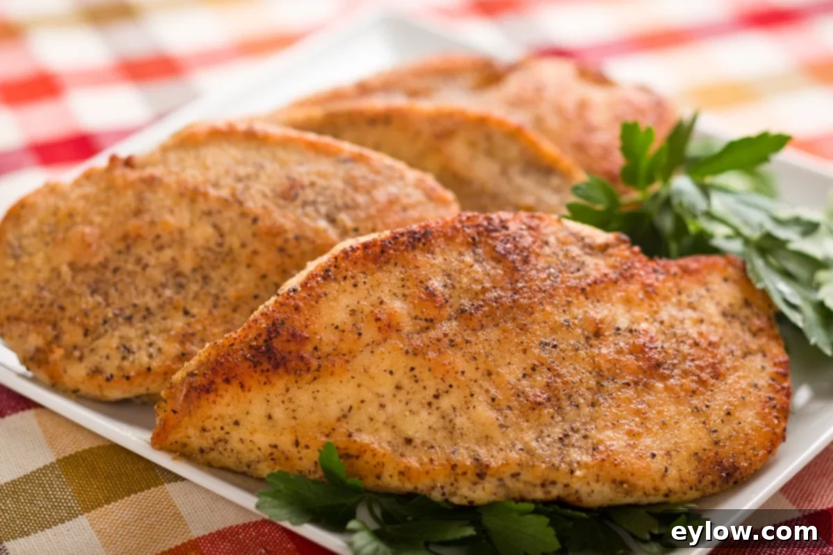 Golden crispy chicken breasts cutlets on a plate with parsley leaves.