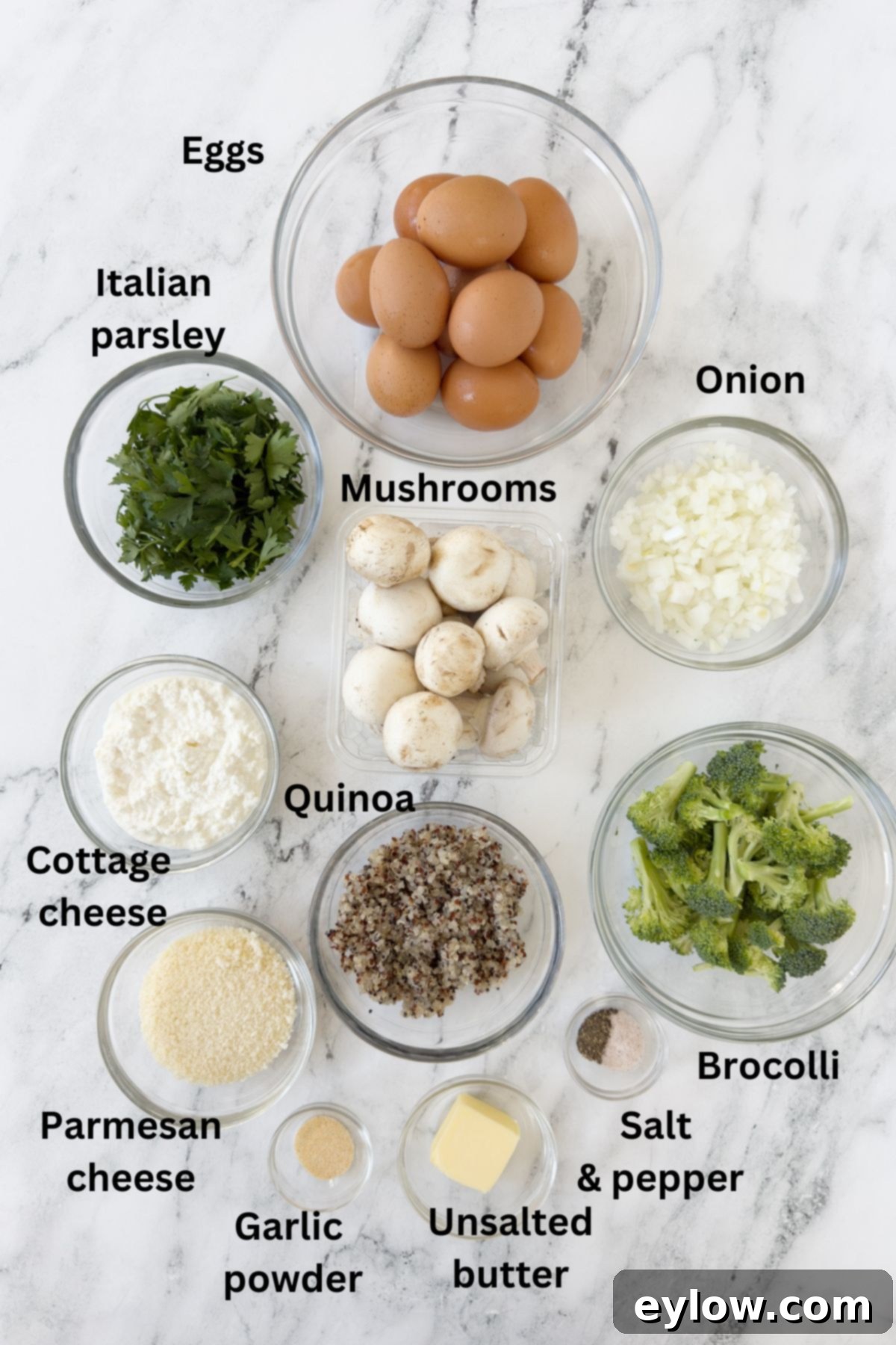 Ingredients for a breakfast egg casserole in prep bowls on the counter with mushrooms, broccoli, and quinoa.