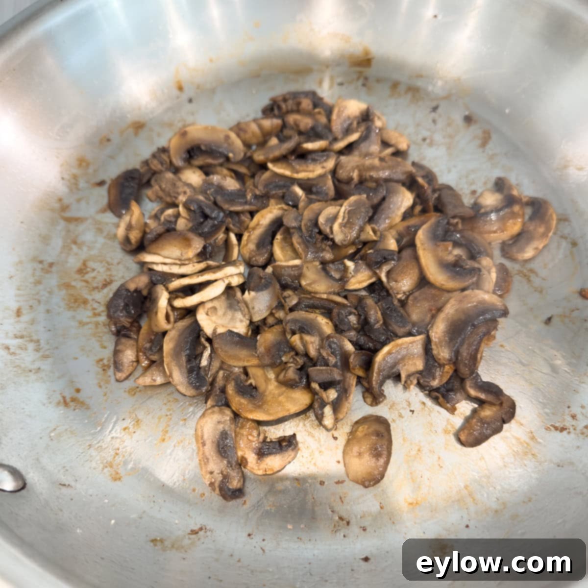 Nicely browned sauteed mushrooms in a stainless steel pan.