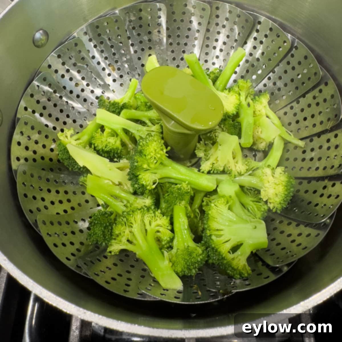 Bright green broccoli florets in a steamer basket.