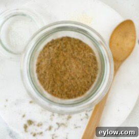 A jar of blended turkey rub ready to go for use with a woodem spoon.
