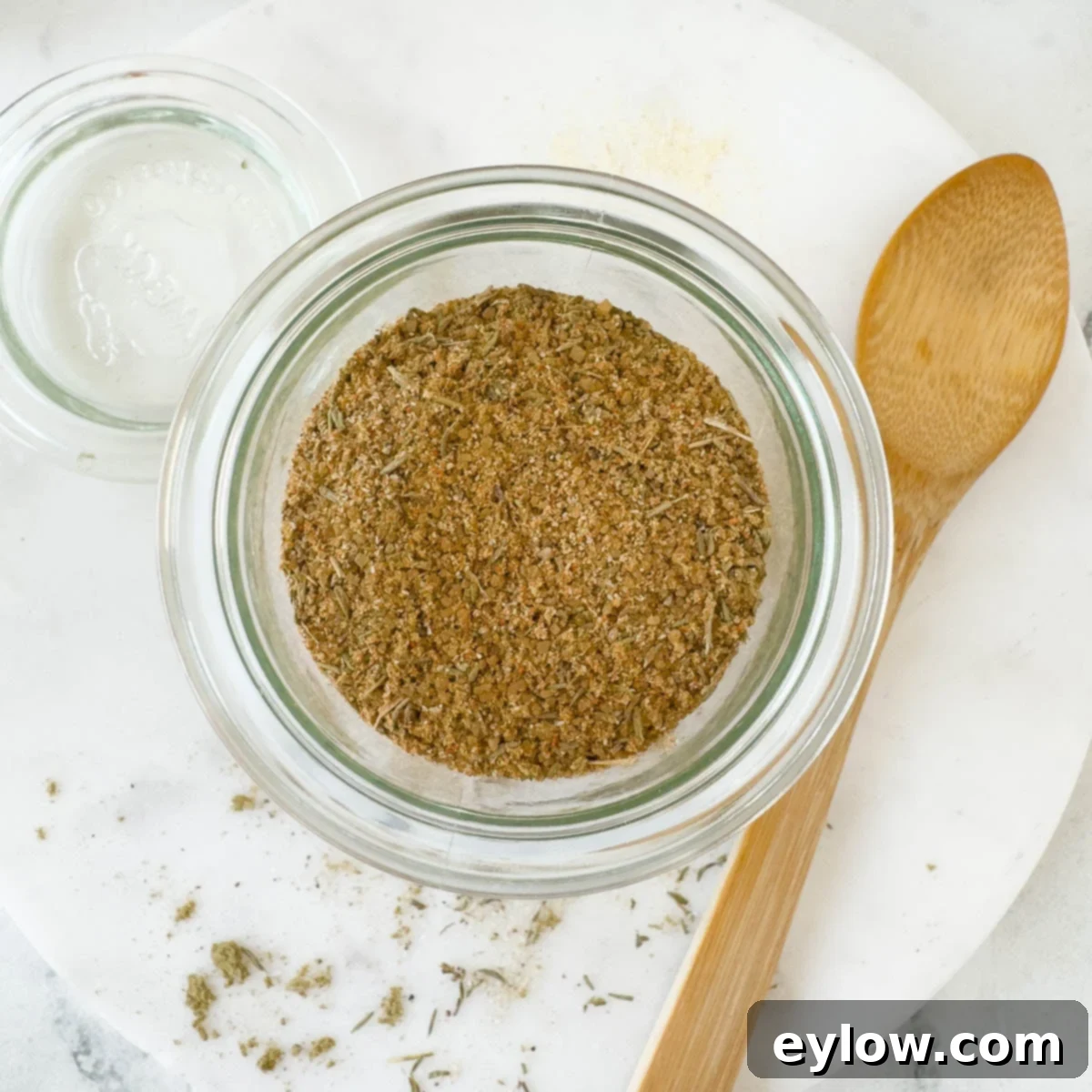 A jar of blended turkey rub ready to go for use with a woodem spoon. 