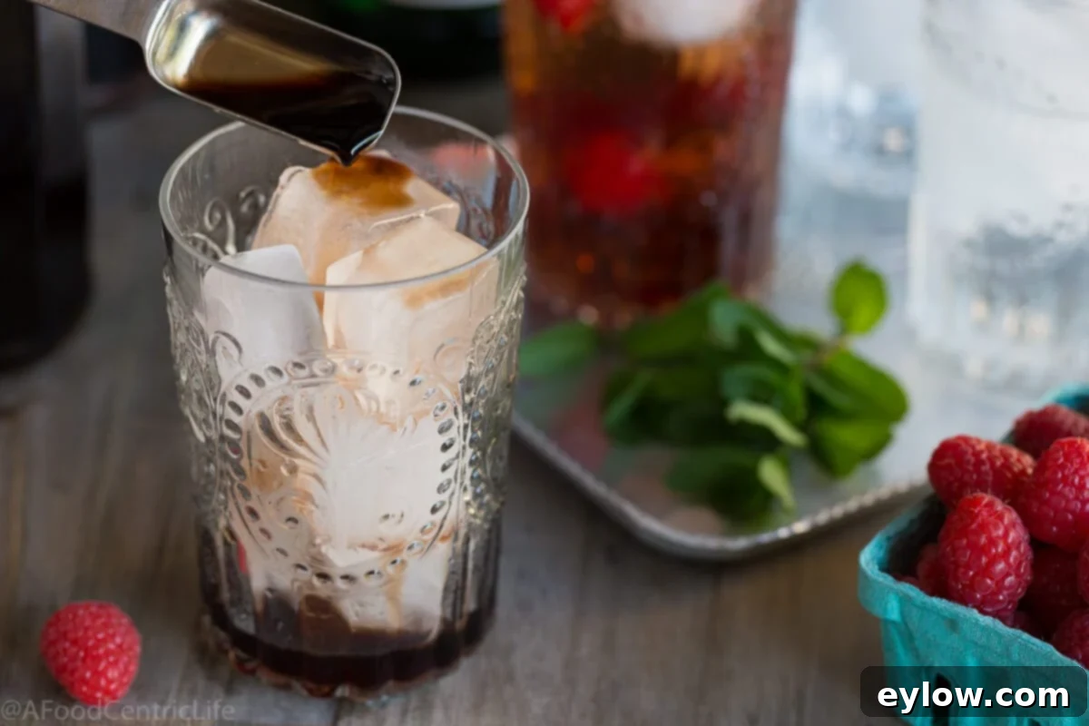 Raspberry Refresher: A Guilt-Free Mocktail 4 Adding raspberry to a drink glass with ice to make a shrub vinegar drink.