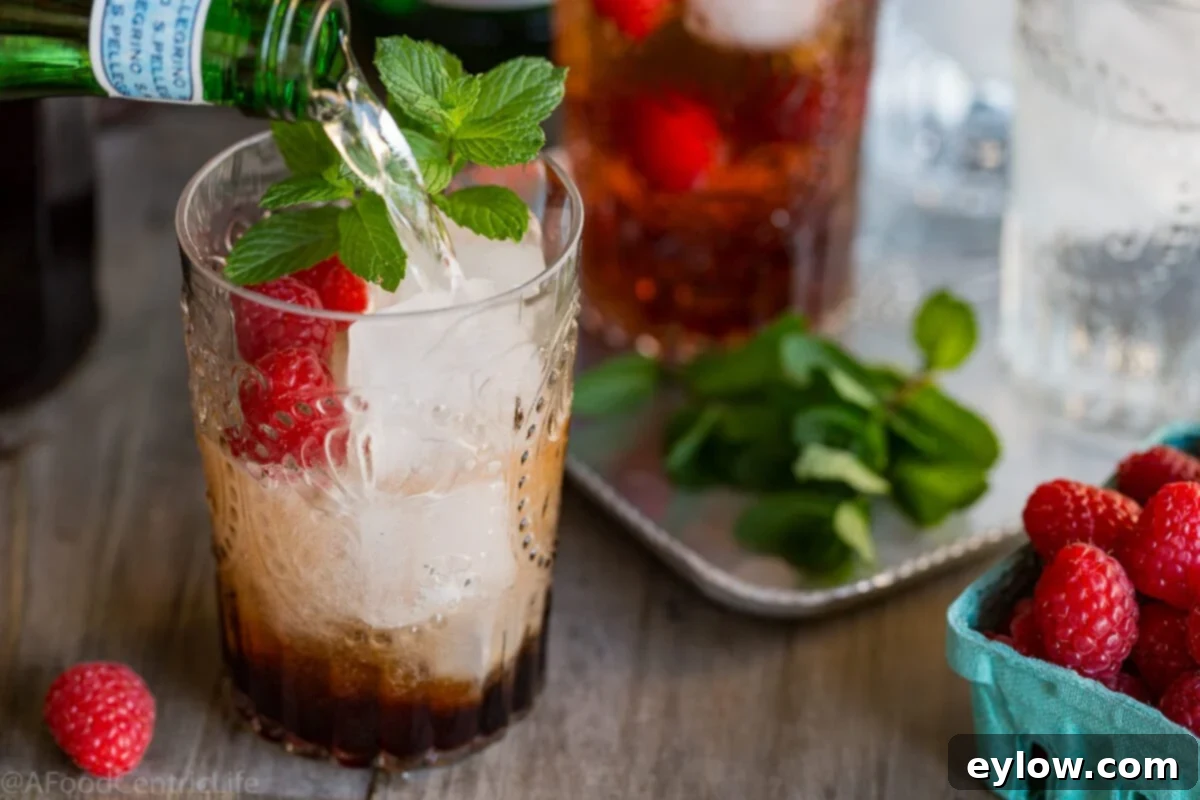 Raspberry Refresher: A Guilt-Free Mocktail 5 Adding sprakling water to a glass of ice and raspberry vinegar to make a shrub vinegar mocktail.