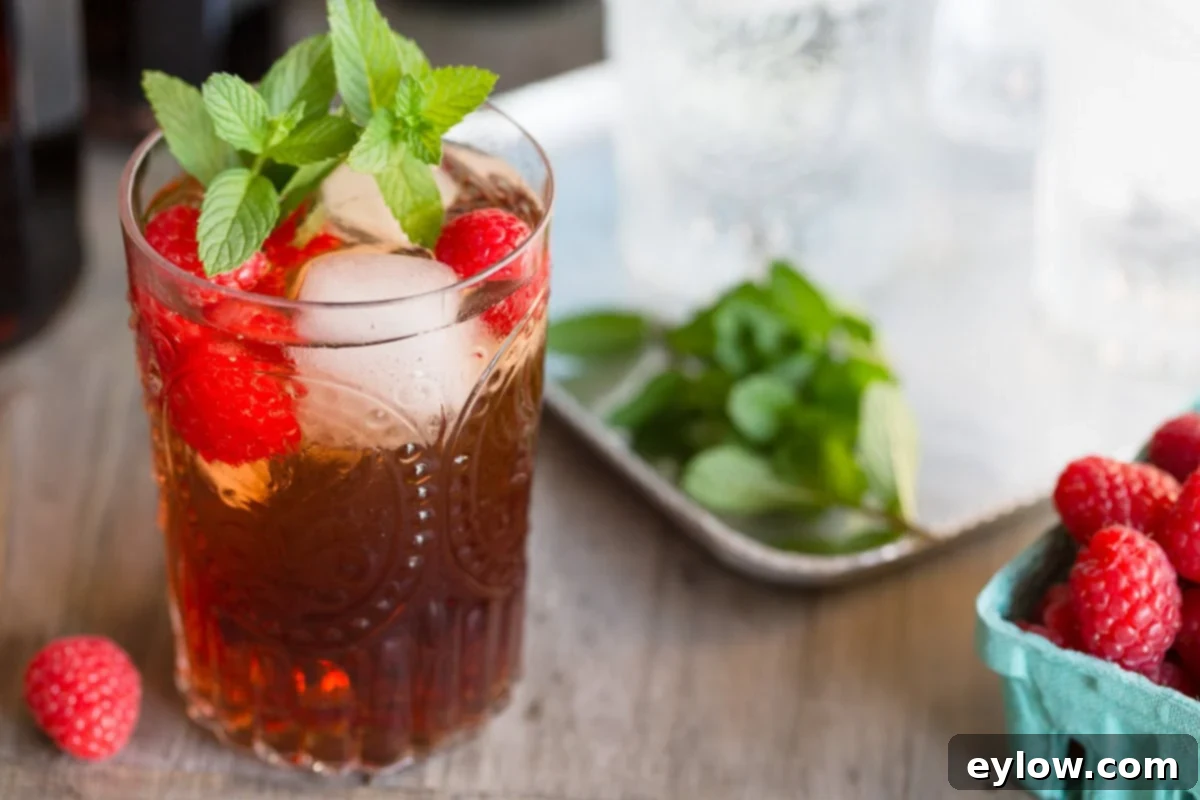 Raspberry Refresher: A Guilt-Free Mocktail 7 A raspberry shrub vinegar mocktail on a gray wood counter with fresh berries and mint.