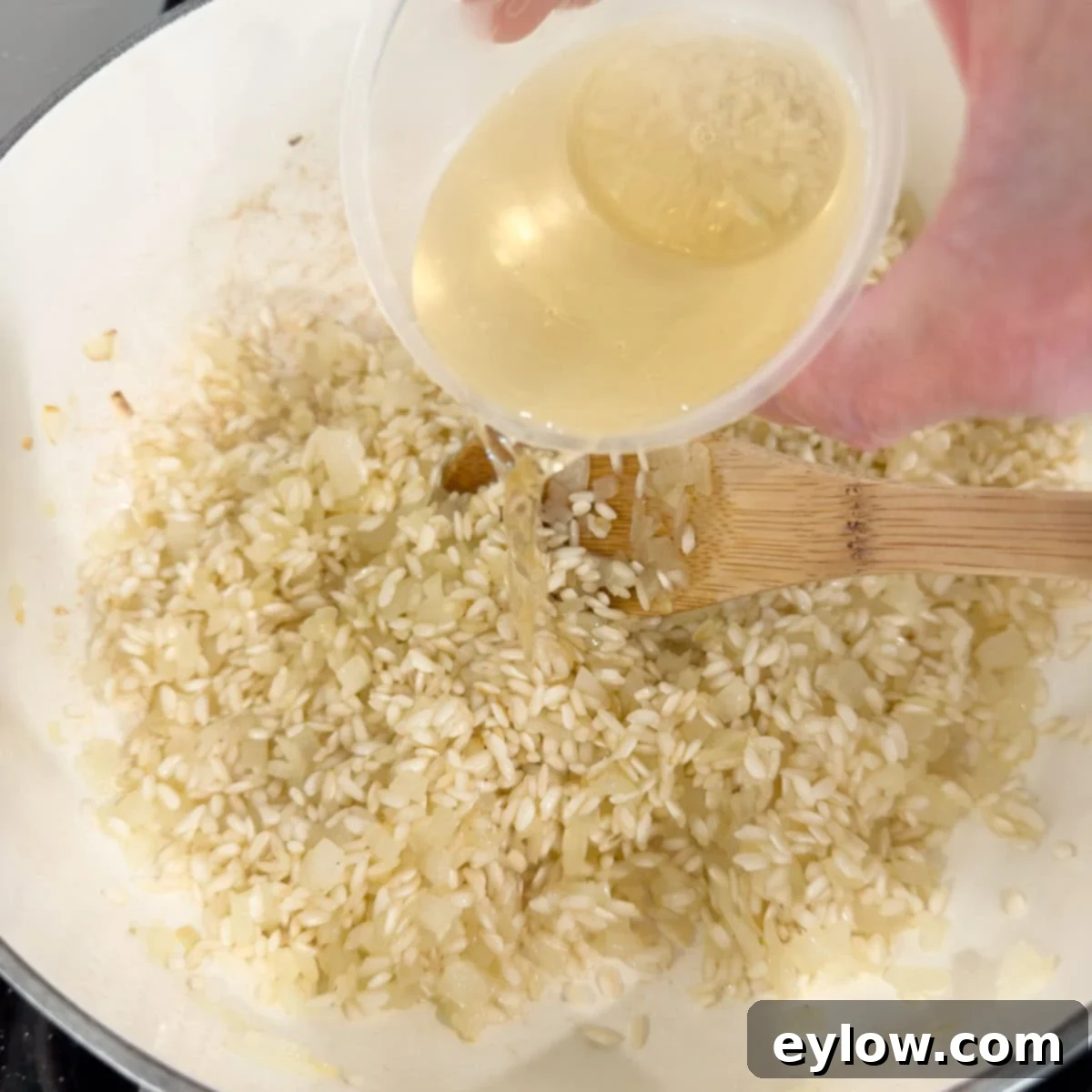 Deglazing a pan of Italian rice for risotto with white wine.