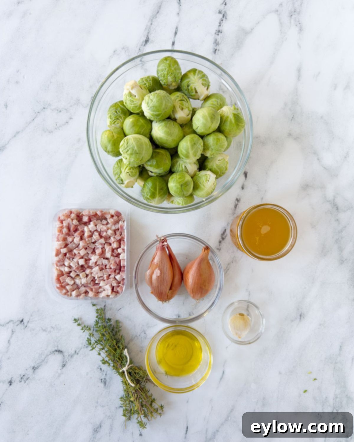 Golden Brussels Sprouts with Crispy Pancetta 3 A vibrant flat lay showcasing the raw ingredients needed for Brussels Sprouts with Pancetta: fresh green Brussels sprouts, diced pancetta, a bowl of rich broth, fragrant herbs, and a bottle of olive oil.